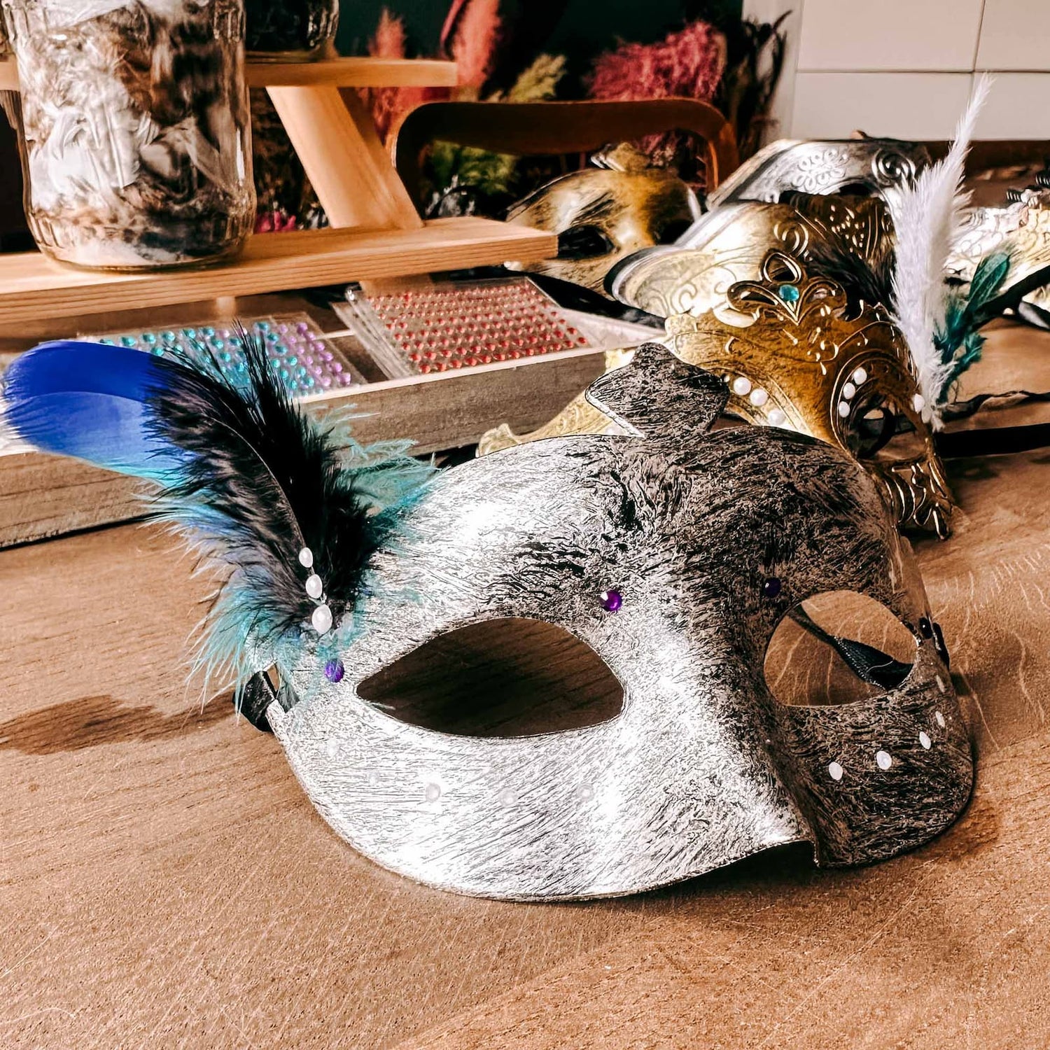 Silberne DIY Maske mit bunten Federn als Dekor beim kreativen Masken Workshop von GRIMMS GARTEN, Teamevent in Berlin
