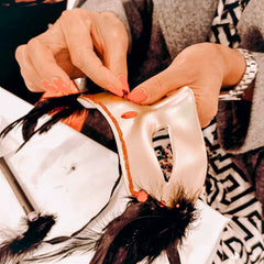 Hand klebt Glitzersteine auf goldene DIY Maske beim kreativen Masken Workshop von GRIMMS GARTEN, Teamevent in Berlin