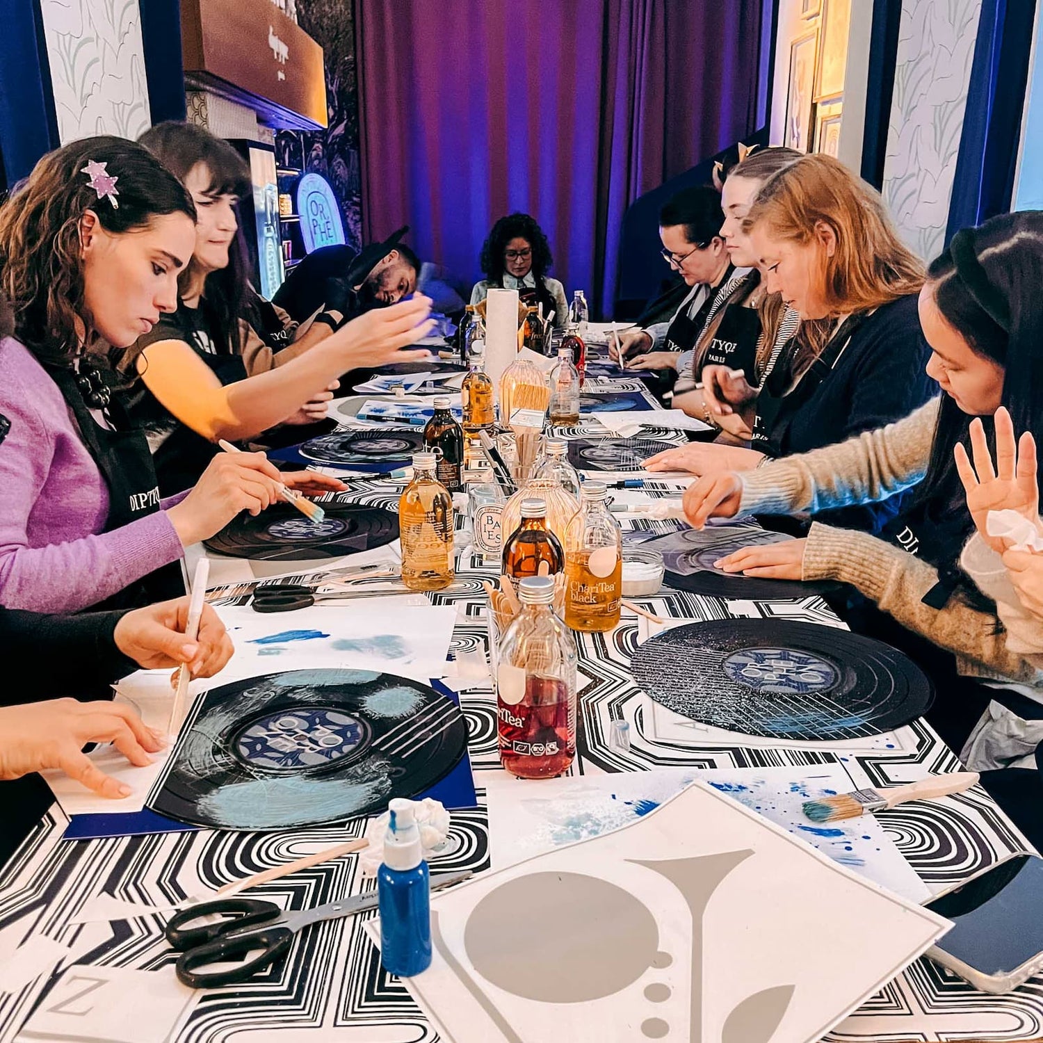 Mehrere Personen bemalen Schallplatten am Tisch mit Farben und Materialien beim Vinylplatten bemalen Workshop von GRIMMS GARTEN, Kreativkurs in Berlin
